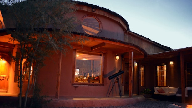 A house with a large window, a telescope, and a cozy seating area.