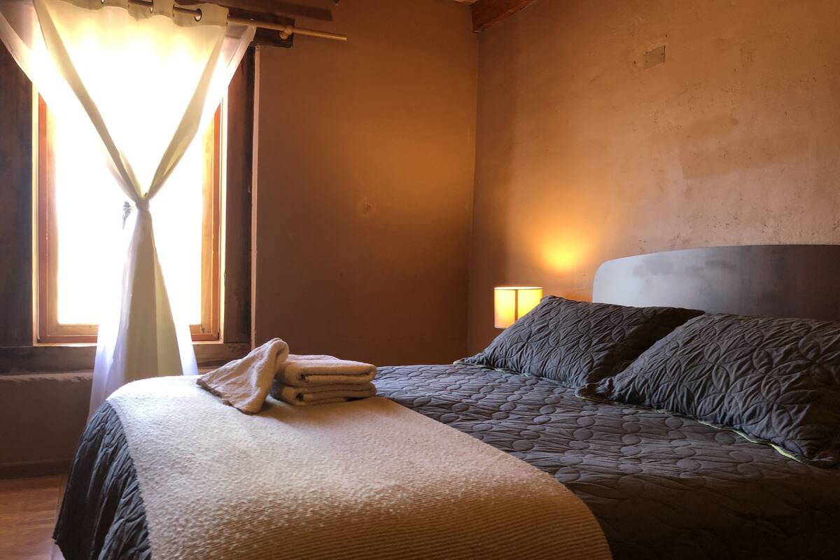 A bedroom with a bed, a bedside lamp, and a window with curtains.