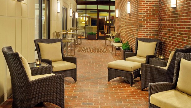 Un patio al aire libre con muebles de mimbre y paredes de ladrillo.