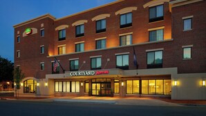 Un hotel Courtyard Marriott con fachada de ladrillo, múltiples ventanas y una entrada bien iluminada.
