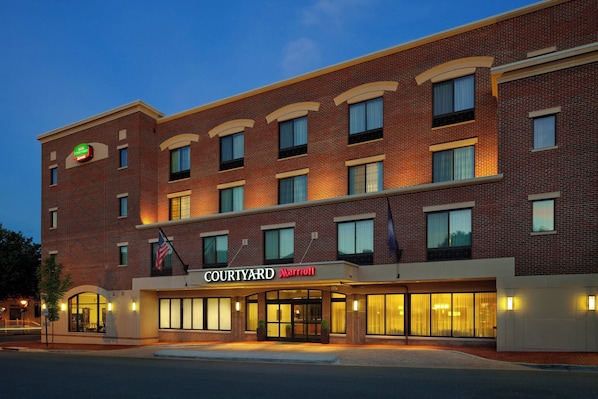 Un hôtel Courtyard Marriott avec une façade en briques, de nombreuses fenêtres et une entrée bien éclairée.