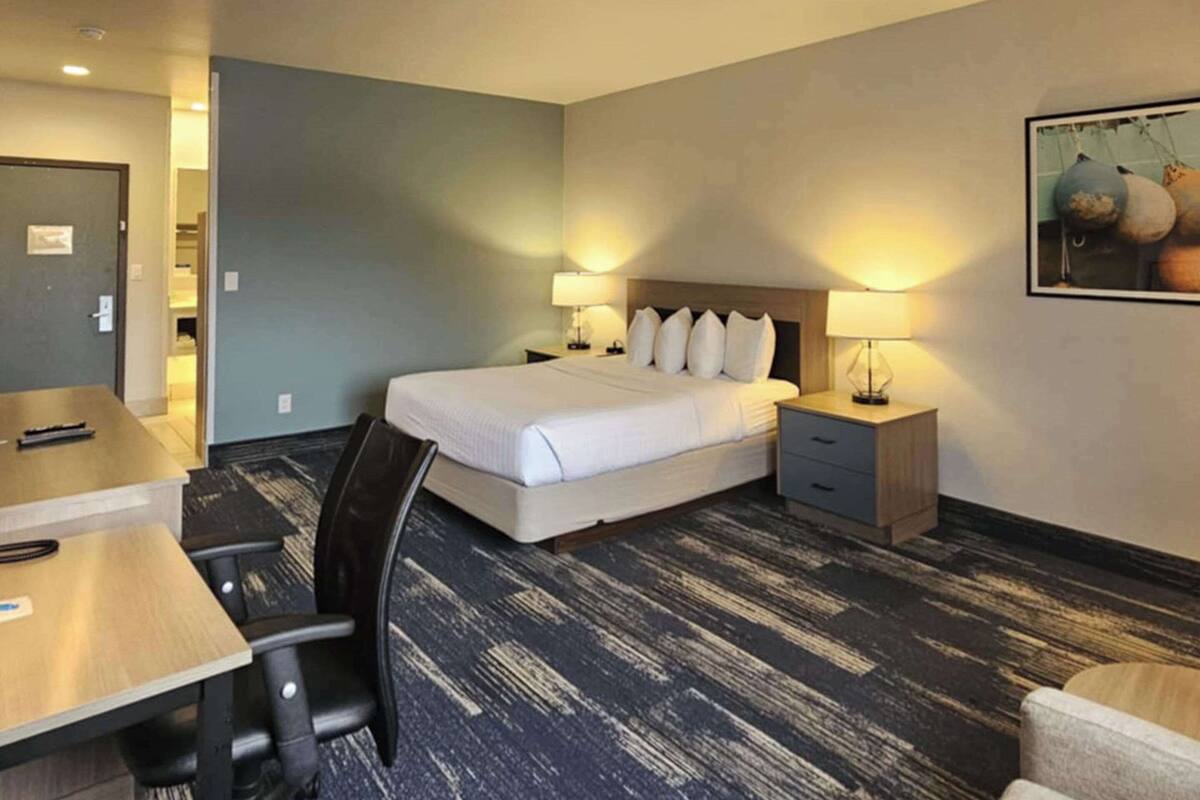 A hotel room with a bed, bedside tables, a desk, and a chair.