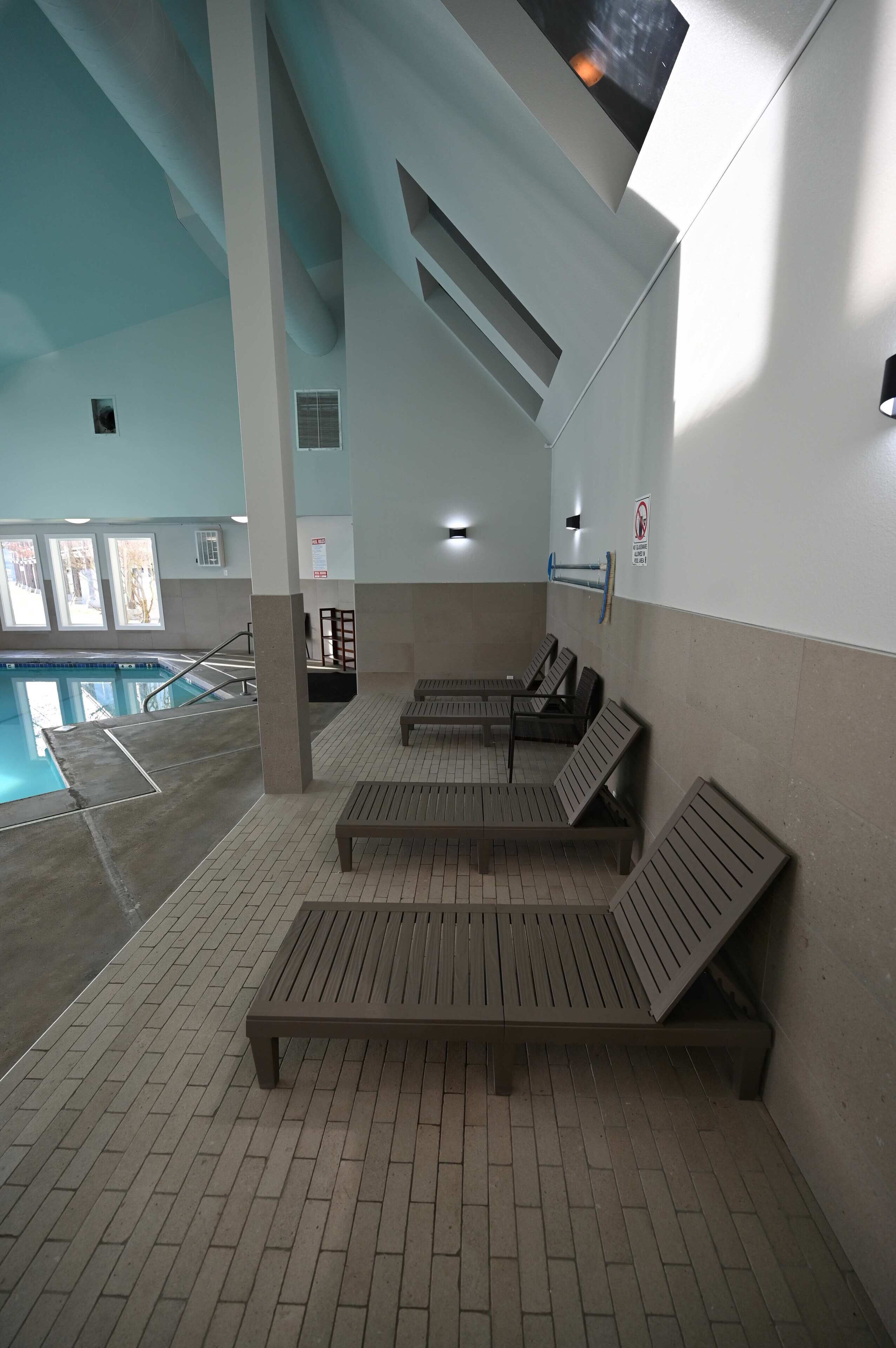 Una zona de piscina con bancos y un trampolín.