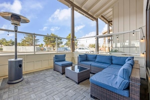 An outdoor patio with a seating area, a table, and a heater.