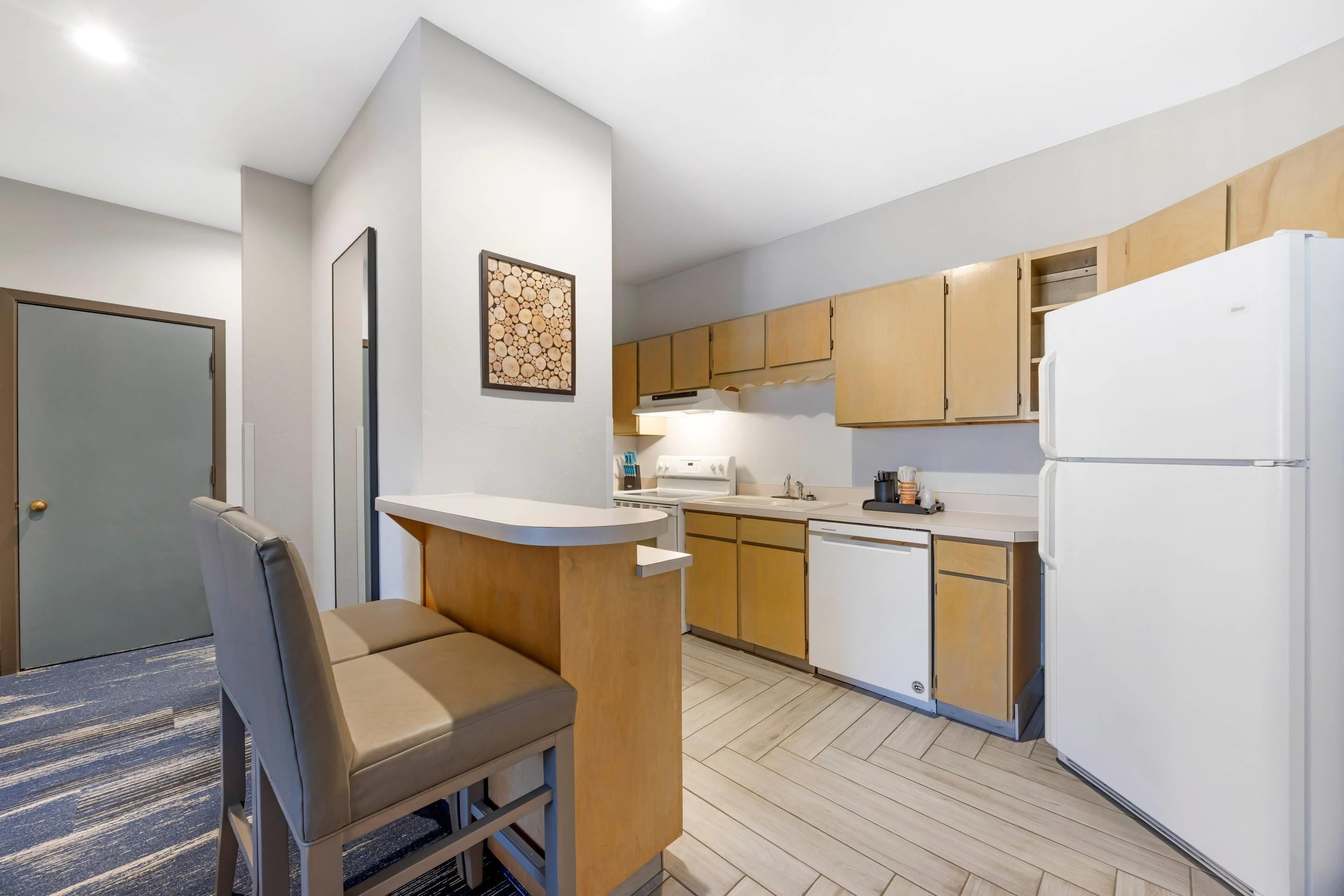 A compact kitchen with wooden cabinets, a white refrigerator, and a built-in oven.