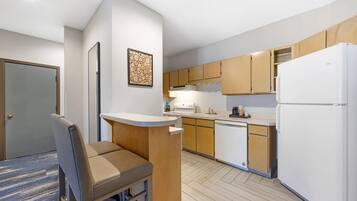 A compact kitchen with wooden cabinets, a white refrigerator, and a built-in oven.