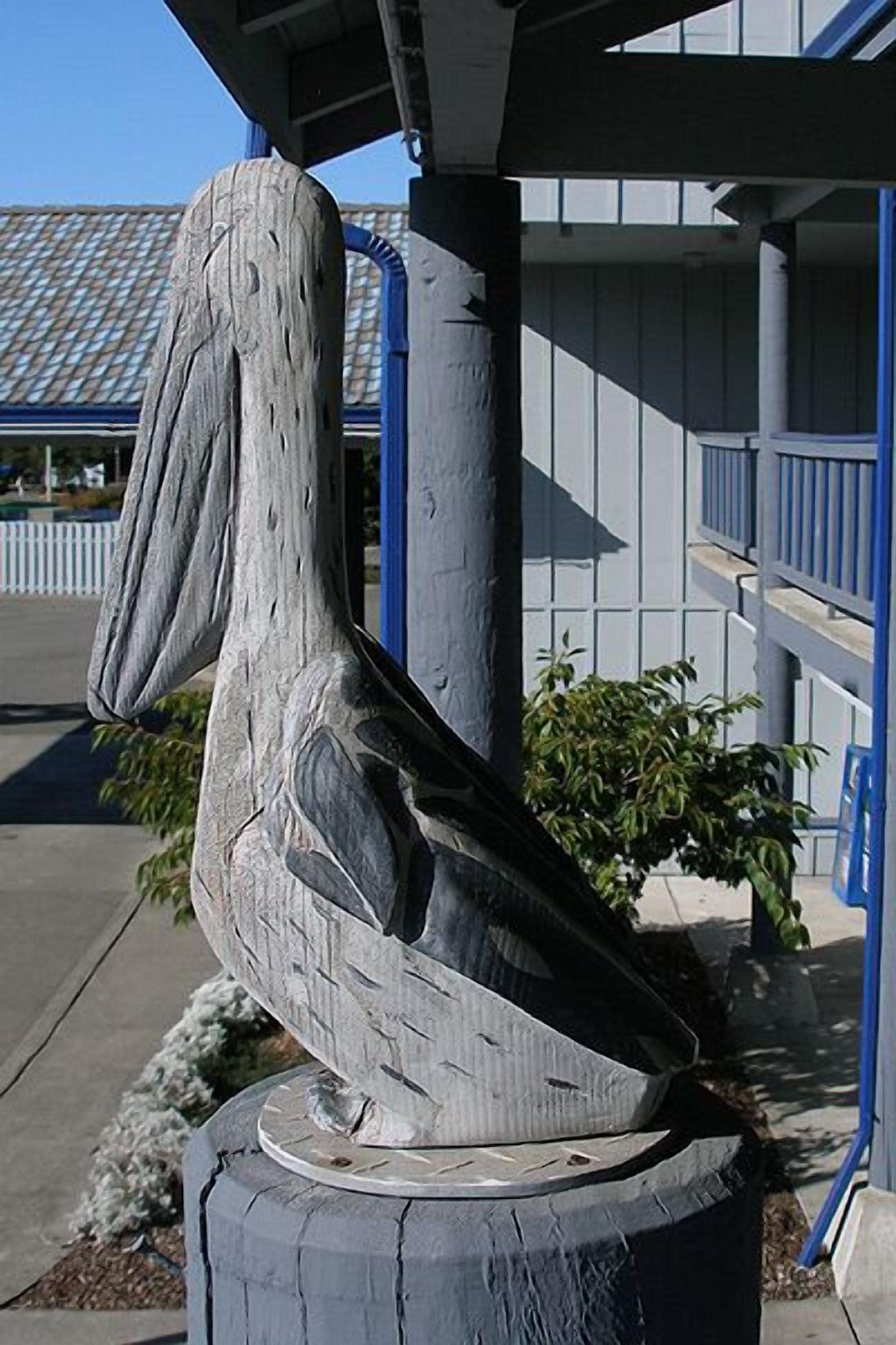 A wooden sculpture of a pelican on a post.