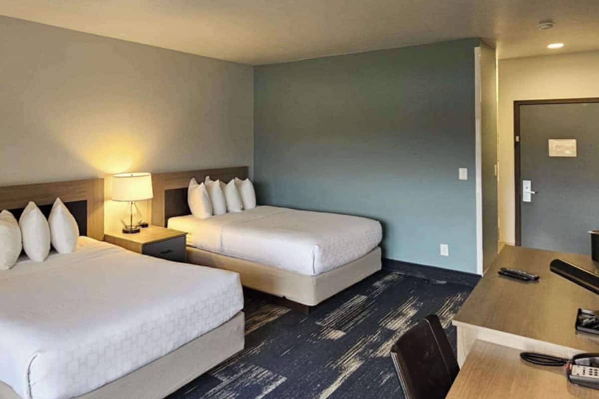 A hotel room with two beds, a desk, and a chair.