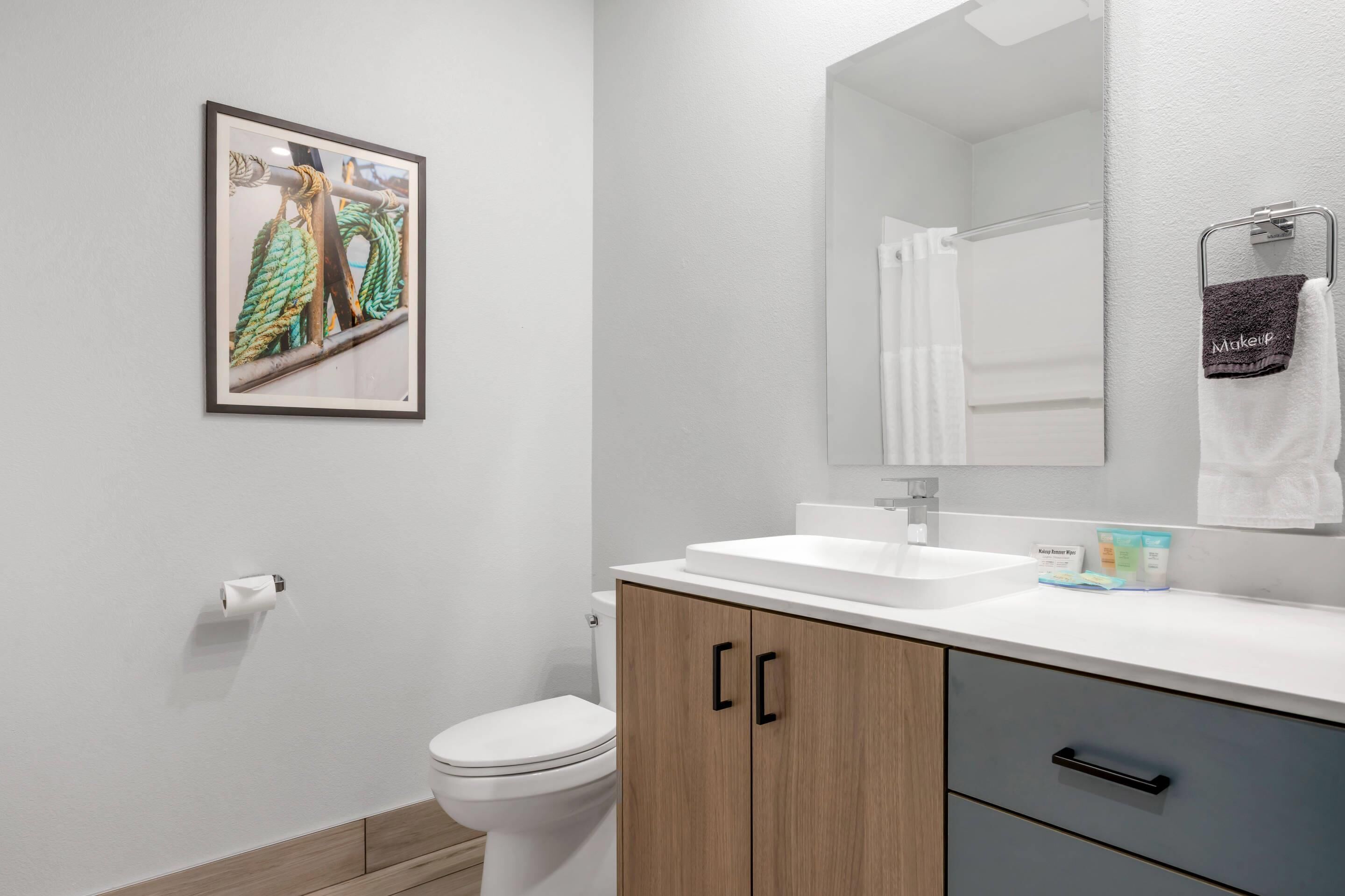 A modern bathroom with a toilet, sink, and cabinet.