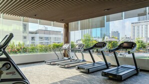A gym with treadmills, large windows, and a view of the cityscape.