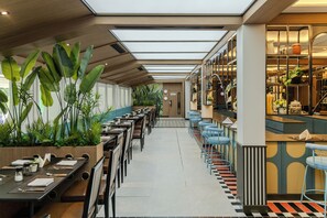 A restaurant with long tables, chairs, and a bar area.