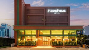 A modern hotel with a prominent sign, large windows, and a well-lit entrance.