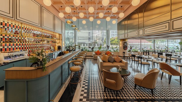 A modern bar area with a checkered floor, bar stools, and a counter with various items.