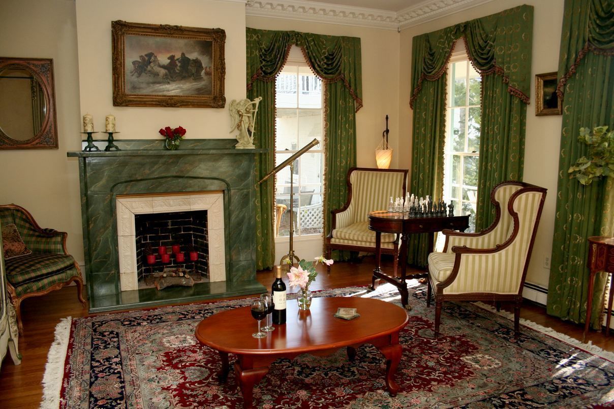 A traditional room with a fireplace, a green patterned rug, a wooden coffee table, and classic furniture.