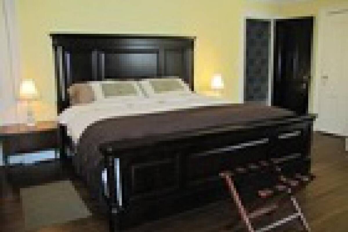 A bedroom with a dark wooden bed, a nightstand with a lamp, and a wardrobe.