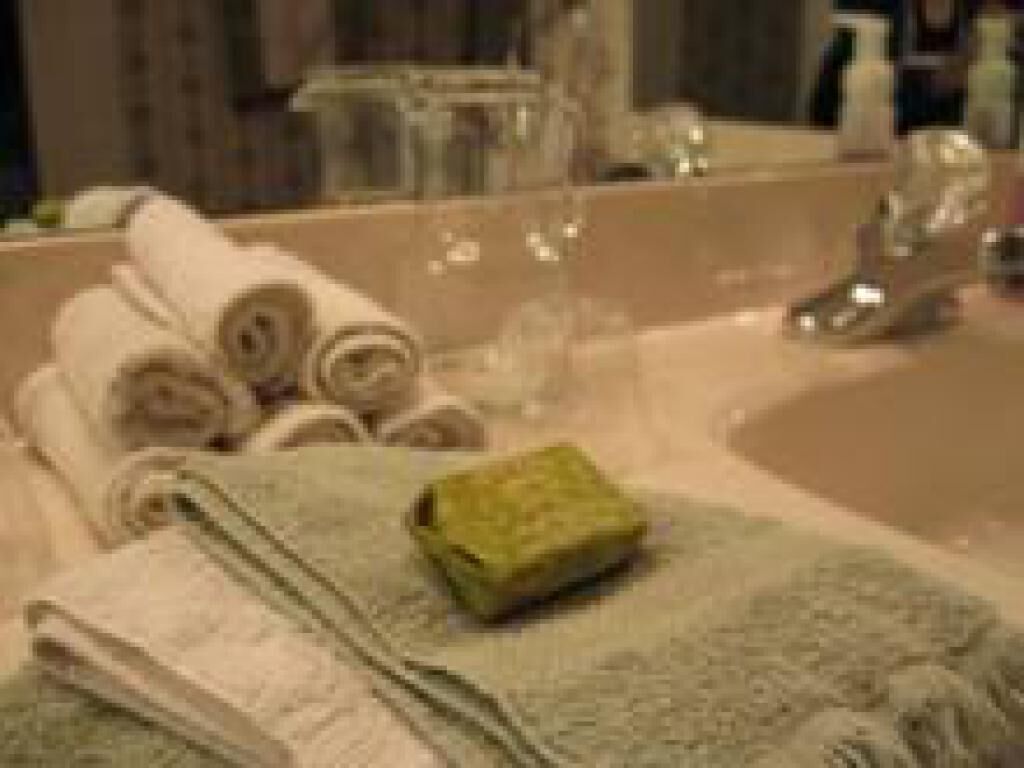 A bathroom with a sink, mirror, and towels.