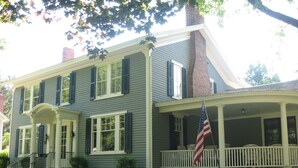 A two-story house with a porch, a flag, and a brick chimney. - Beautiful Valley Guesthouse (Scottsville)