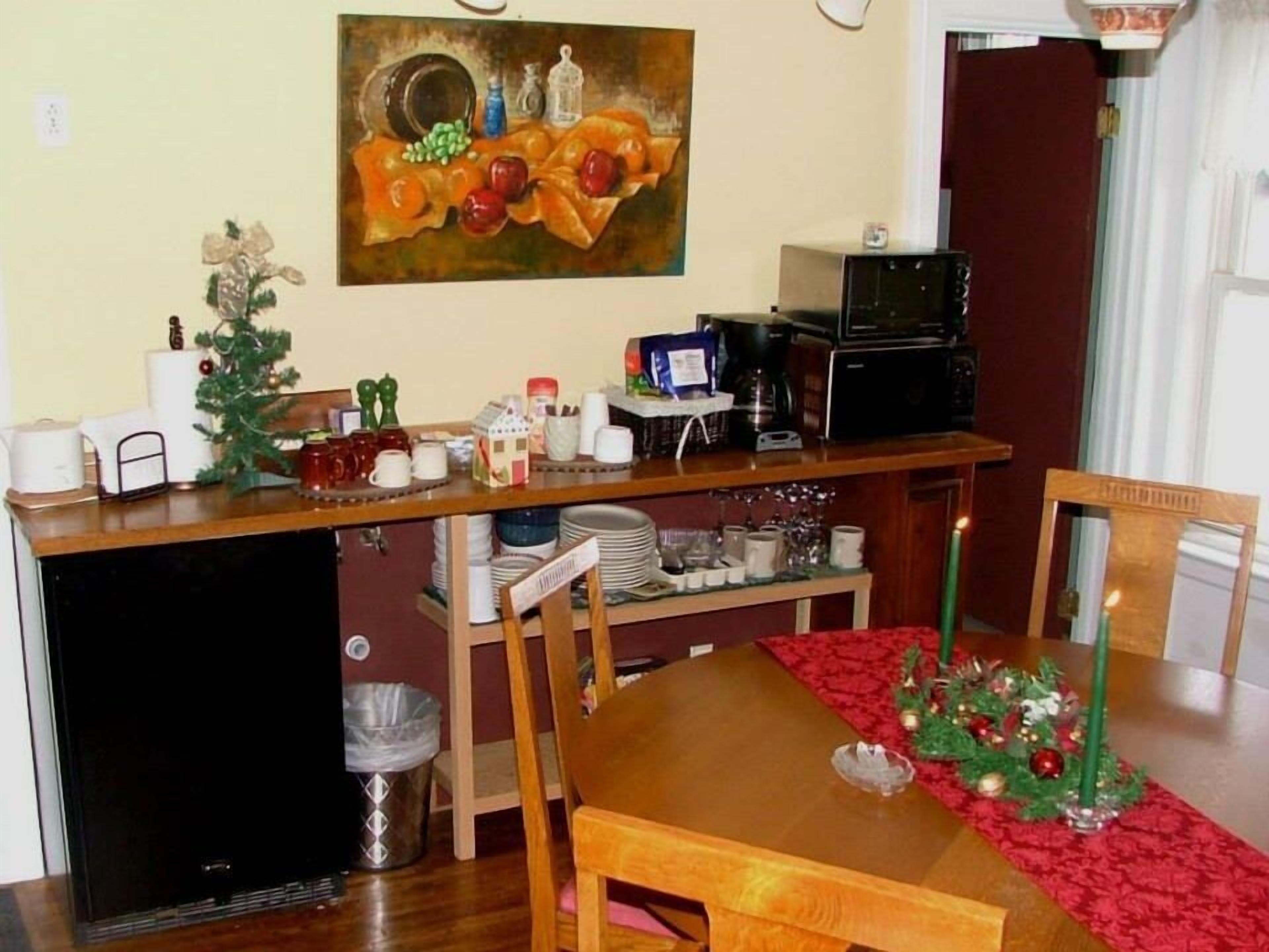 Un comedor con una mesa de madera, sillas, un pequeño árbol de Navidad y un cuadro en la pared.