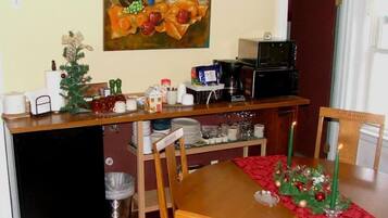 Un comedor con una mesa de madera, sillas, un pequeño árbol de Navidad y un cuadro en la pared.