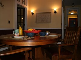 Uma mesa de jantar com cadeiras, um mapa na parede e uma cesta de frutas.