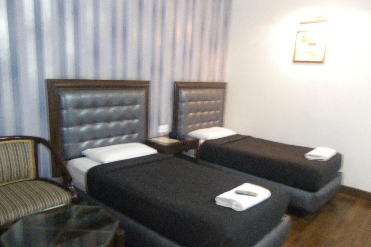 A hotel room with two beds, a small table, and a chair.