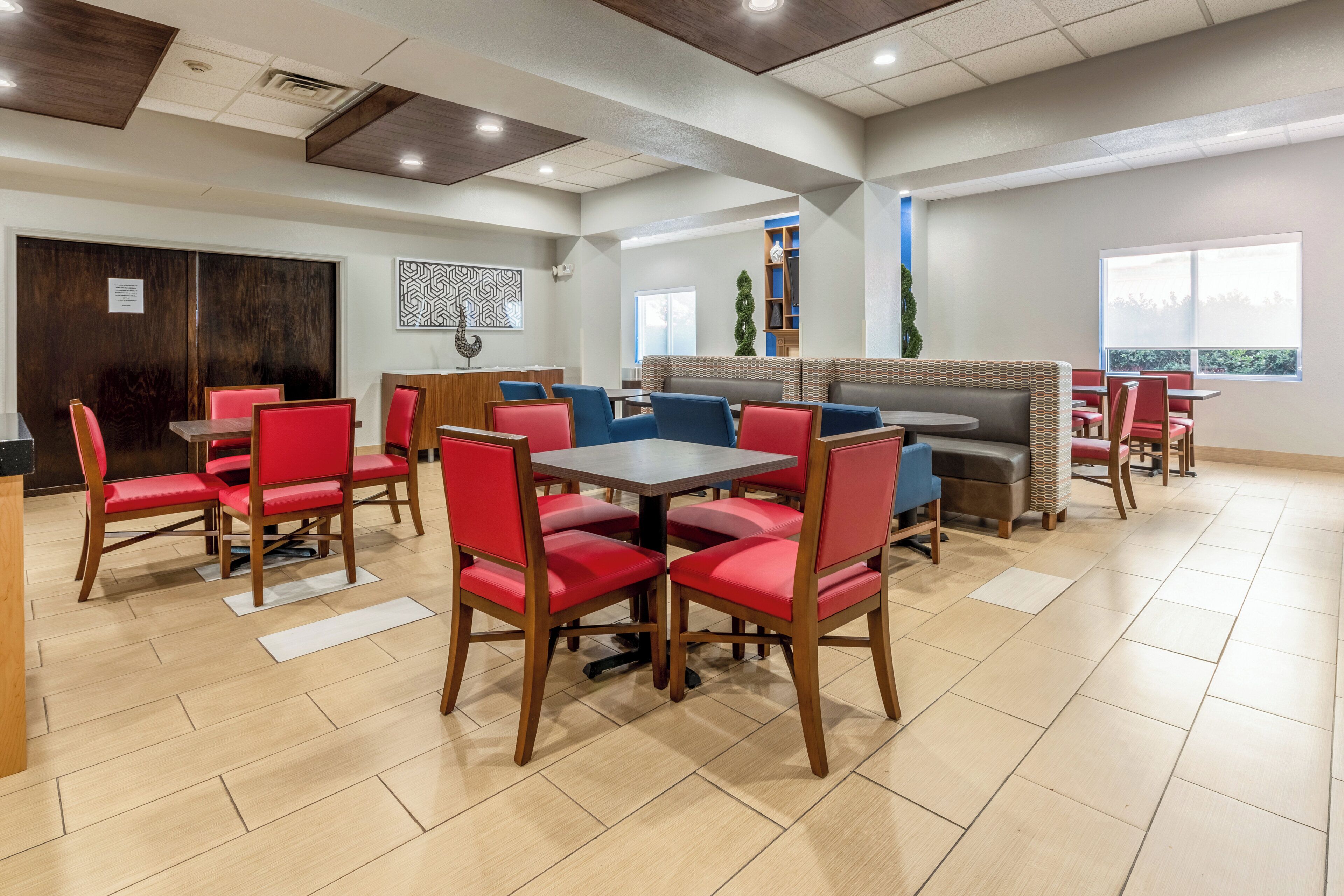 A restaurant with booths and tables, wooden flooring, and a modern ceiling design.