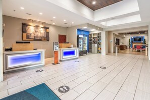 A hotel lobby with reception desks, a vending machine, and a seating area with a TV. - Holiday Inn Express Hotel and Suites Statesville by IHG (Statesville)