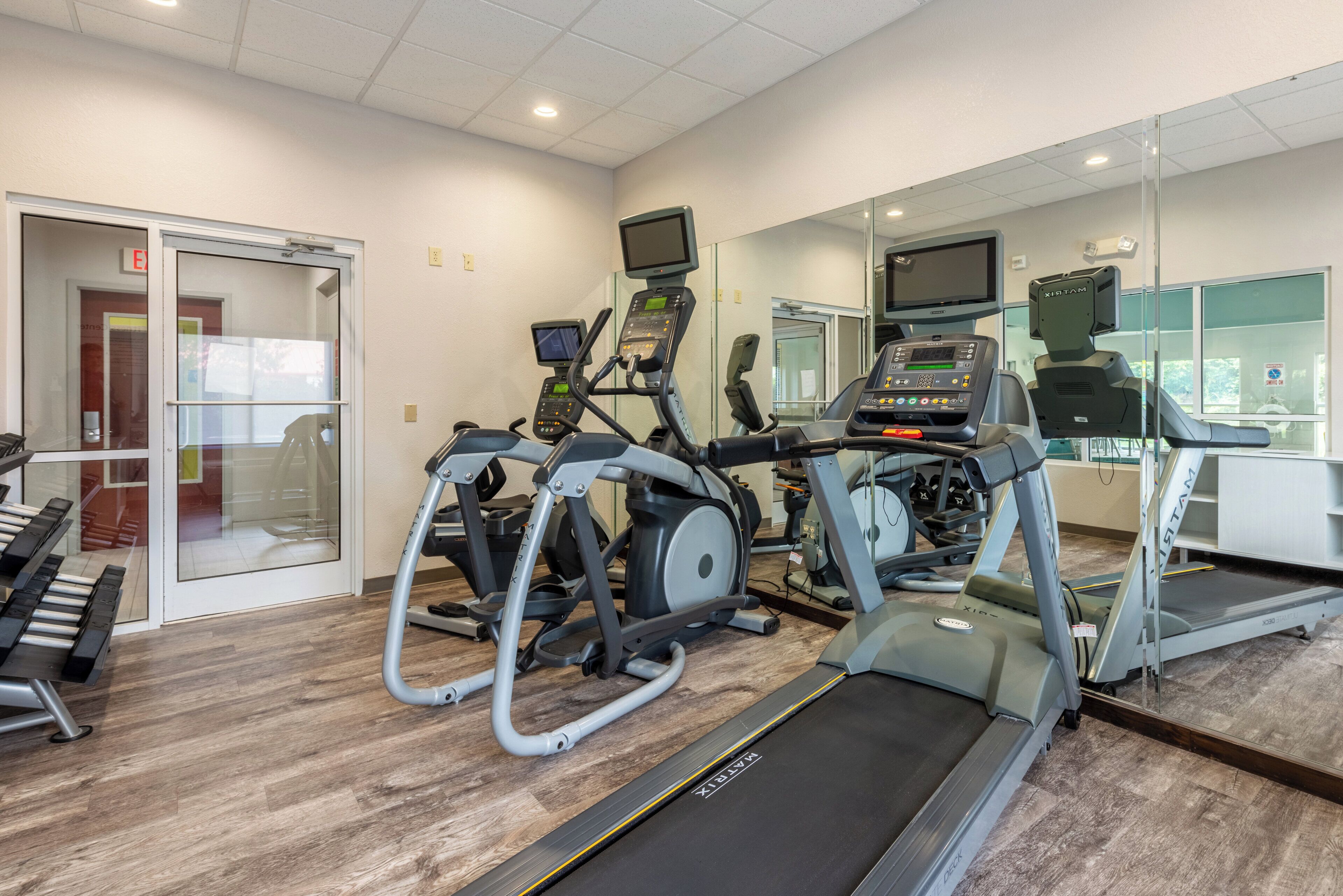 Une salle de sport équipée de tapis de course, d’appareils elliptiques et de vélos d’exercice.