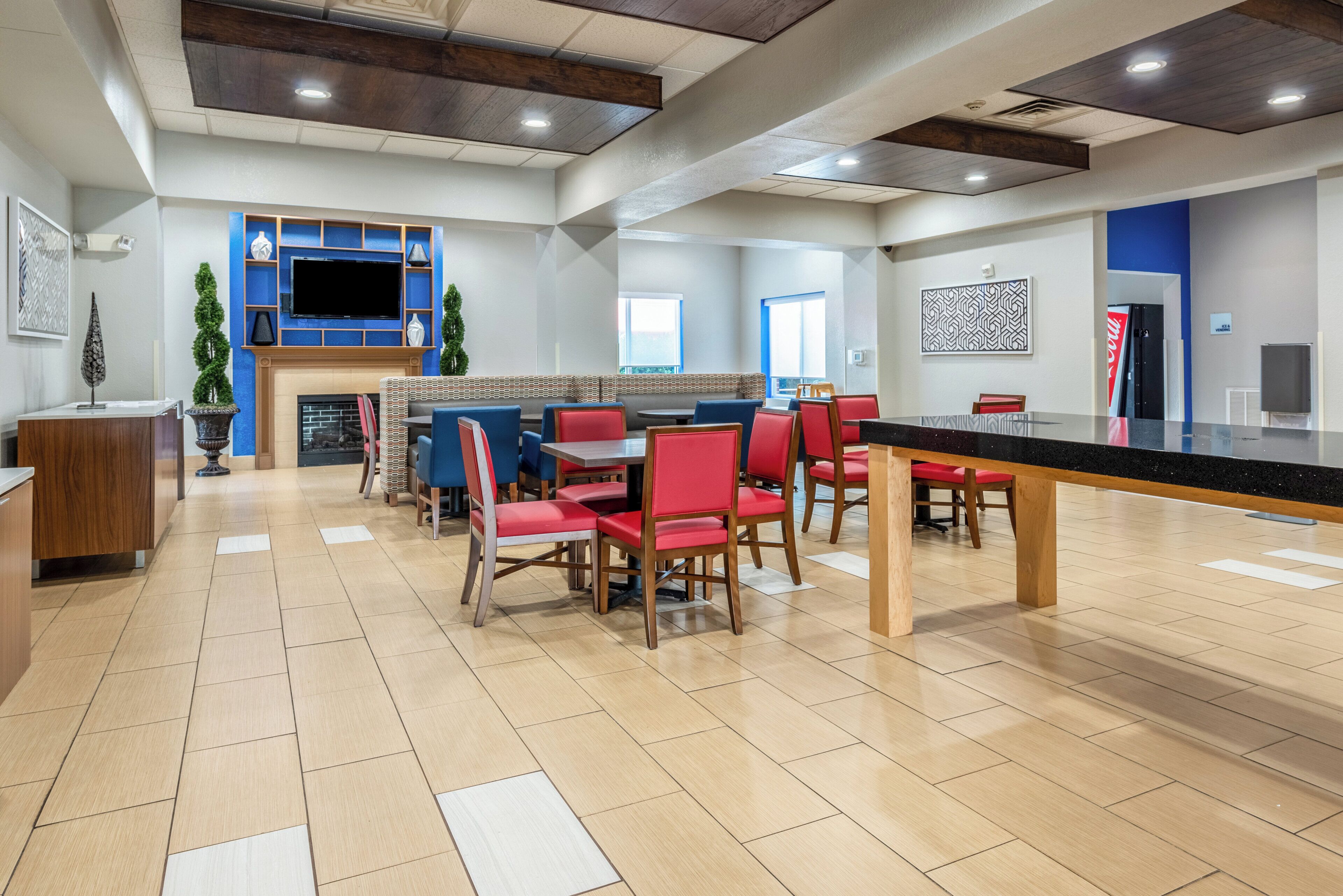 A modern restaurant with a bar area, red seating, and a flat-screen TV mounted on the wall.