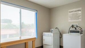 A guest laundry area with a table, two washing machines, and a sign with laundry instructions.