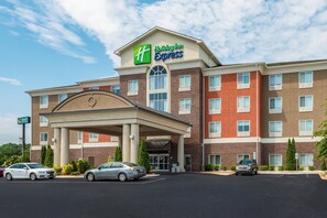 Un hotel con un cartel llamativo de Holiday Inn Express, que presenta fachada de ladrillo y entrada cubierta.