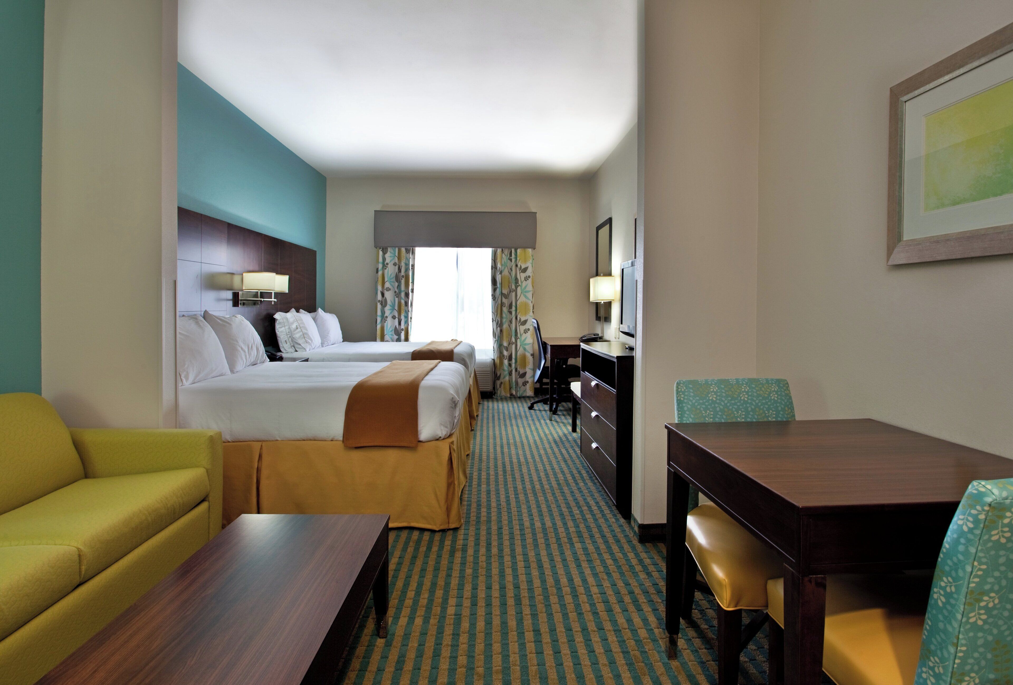 Una habitación de hotel con cama, escritorio, silla, sofá y televisor.