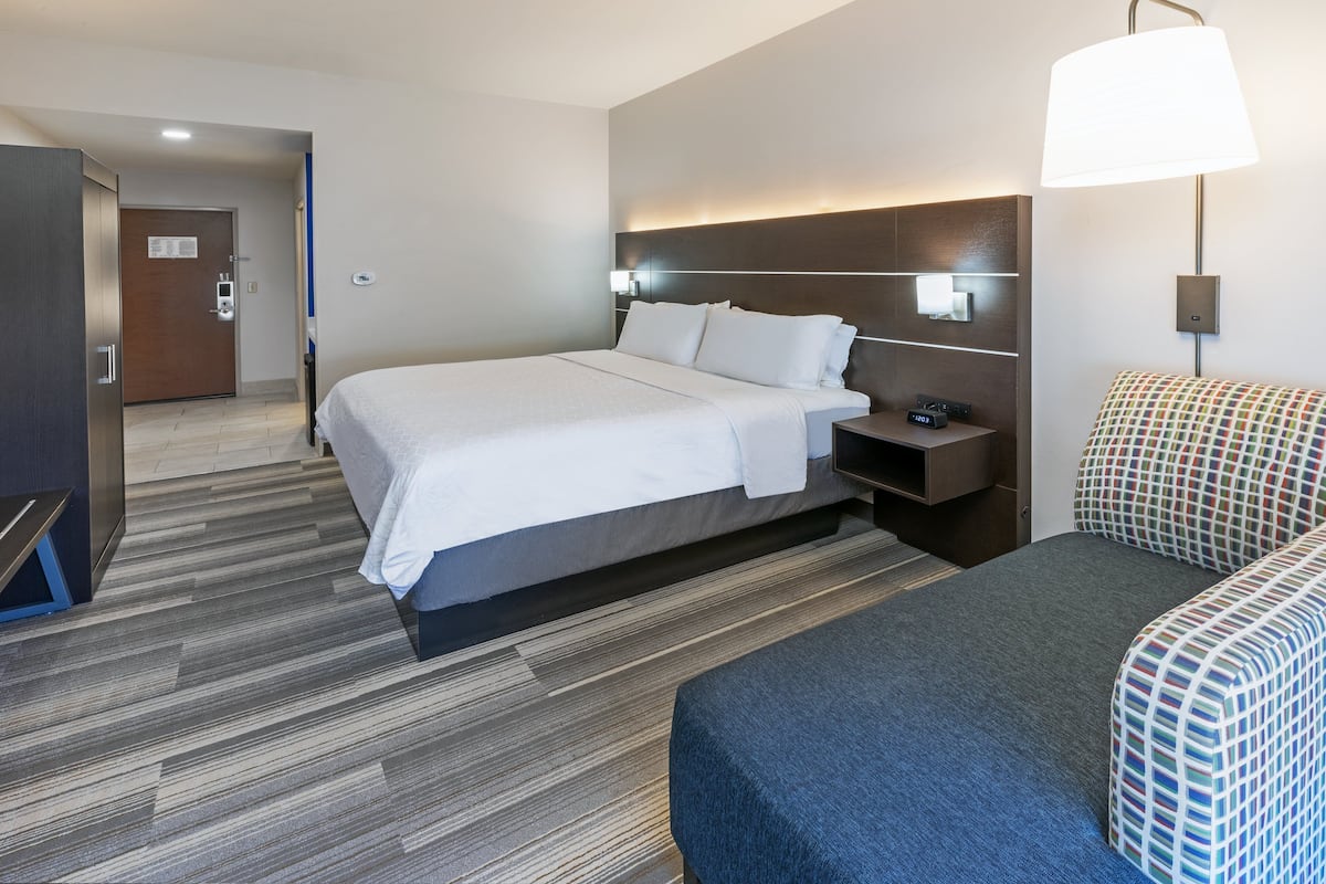 A hotel room with a large bed, bedside tables, a desk, and a chair.