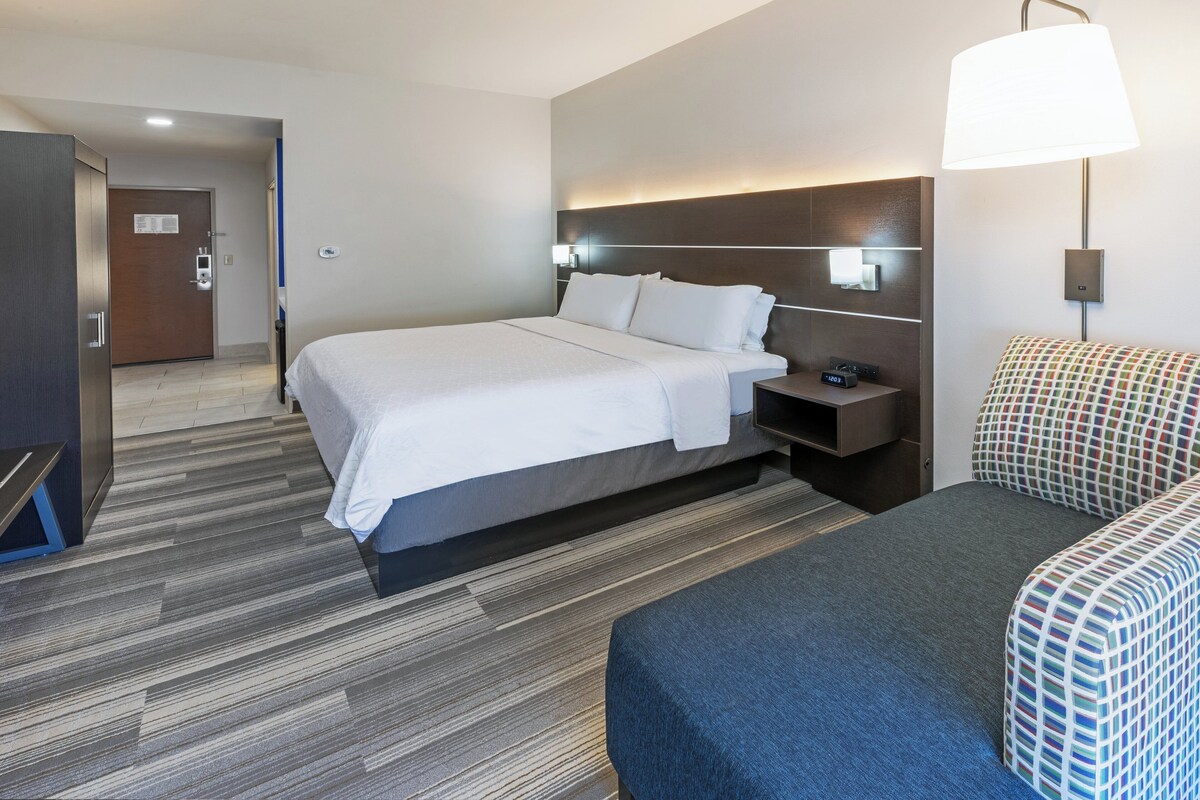 A hotel room with a large bed, bedside tables, a desk, and a chair.