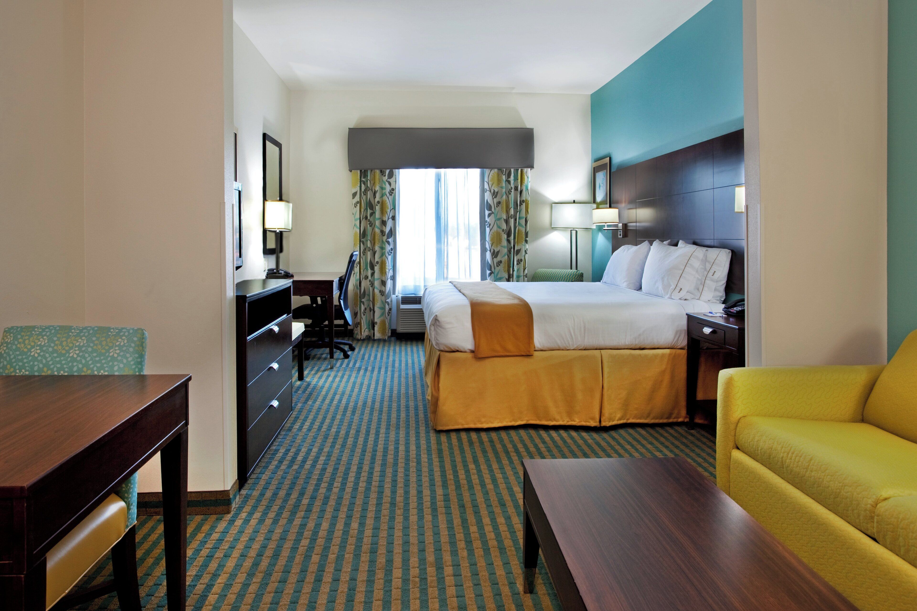 Een hotelkamer met een bed, bureau, stoel, bank en televisie.