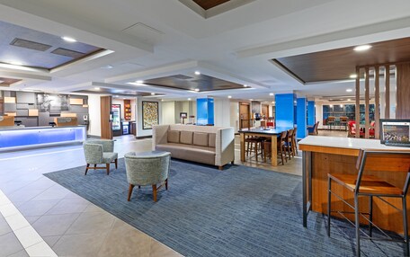 A modern hotel lobby with a reception desk, seating area, and a dining space.