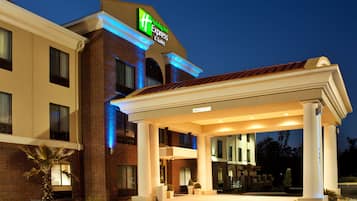 Welcome to Holiday Inn Express & Suites, featuring a classic entrance with a covered canopy and brick facade.