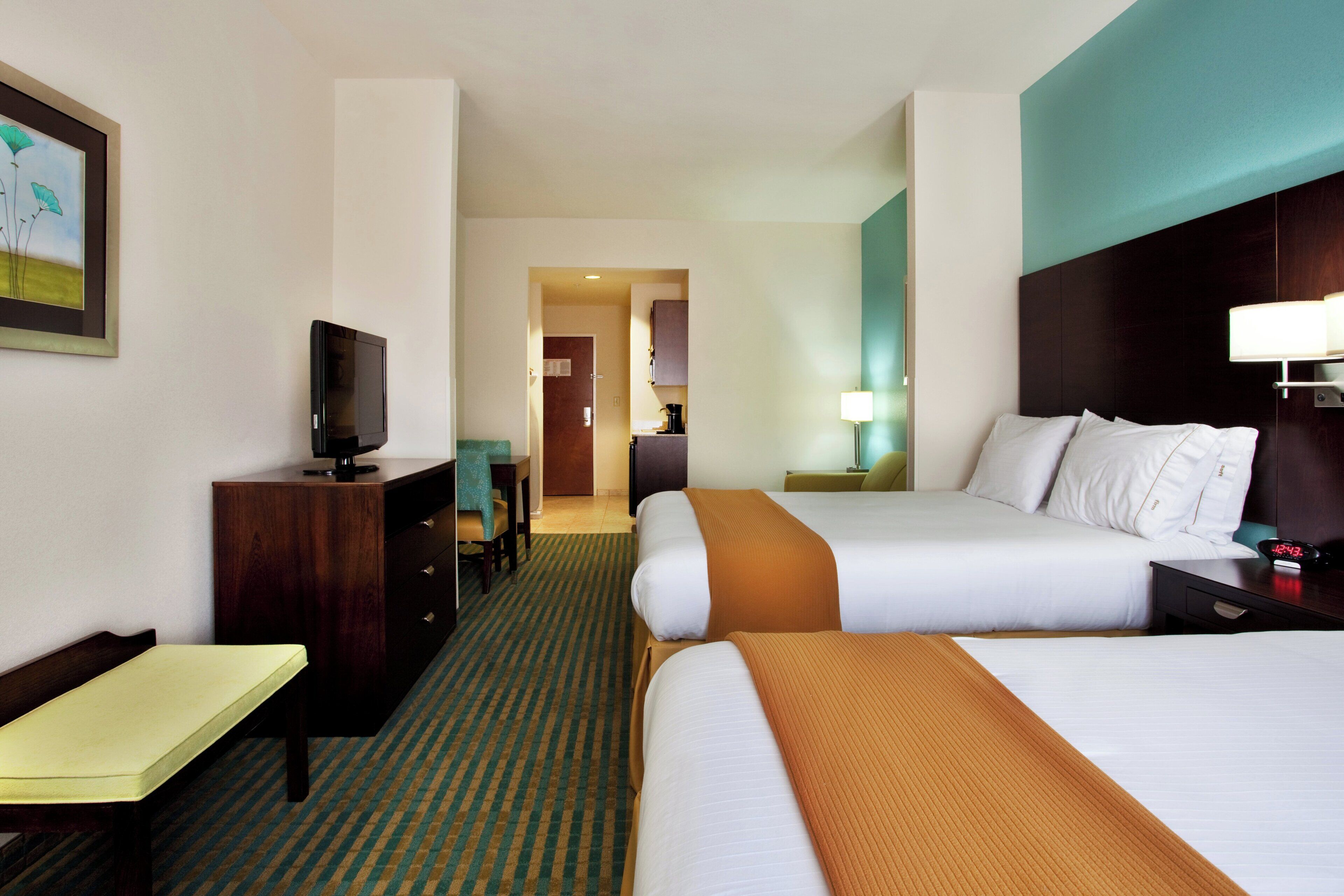 Een hotelkamer met een bed, een bureau, een televisietoestel en een badkamer die door een geopende deur zichtbaar is.