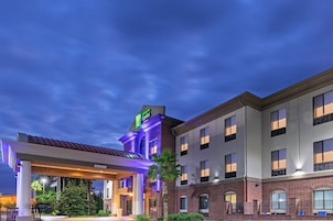 A hotel with a brick facade, a gas station, and a covered parking area.