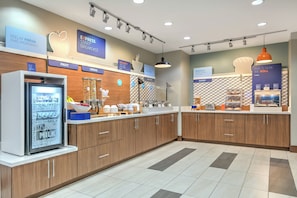 A modern breakfast area with a refrigerated display of yogurt and milk, a fruit section, and a cereal display. - Holiday Inn Express Hotel & Suites Clute - Lake Jackson by IHG (Clute)