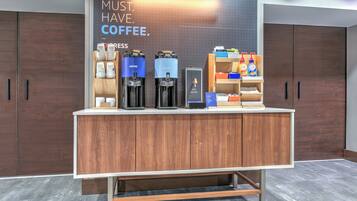 A modern coffee station with espresso machines, a hot water dispenser, and a variety of coffee products.