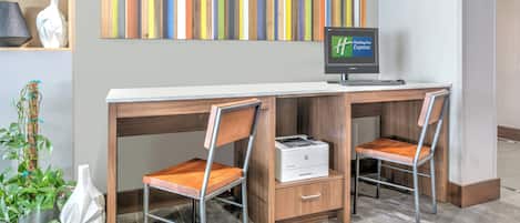 A hotel reception desk with two chairs, a computer monitor, and a printer.
