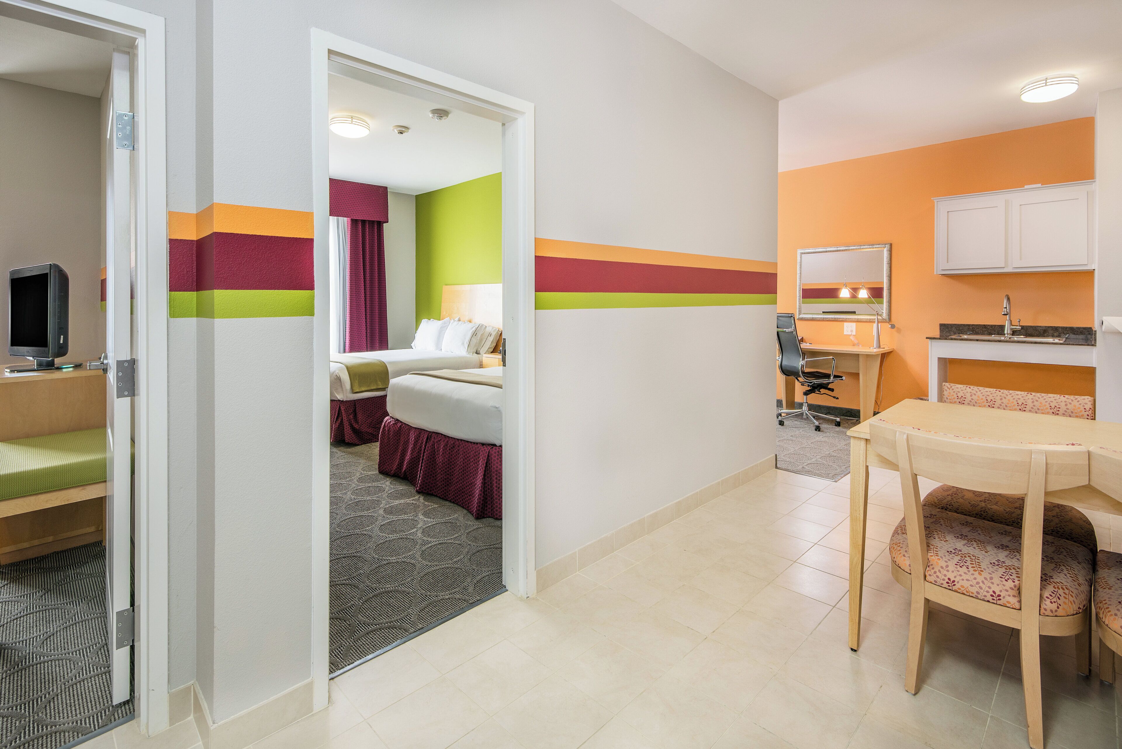 Una habitación de hotel con cama, escritorio, silla, televisor y baño.