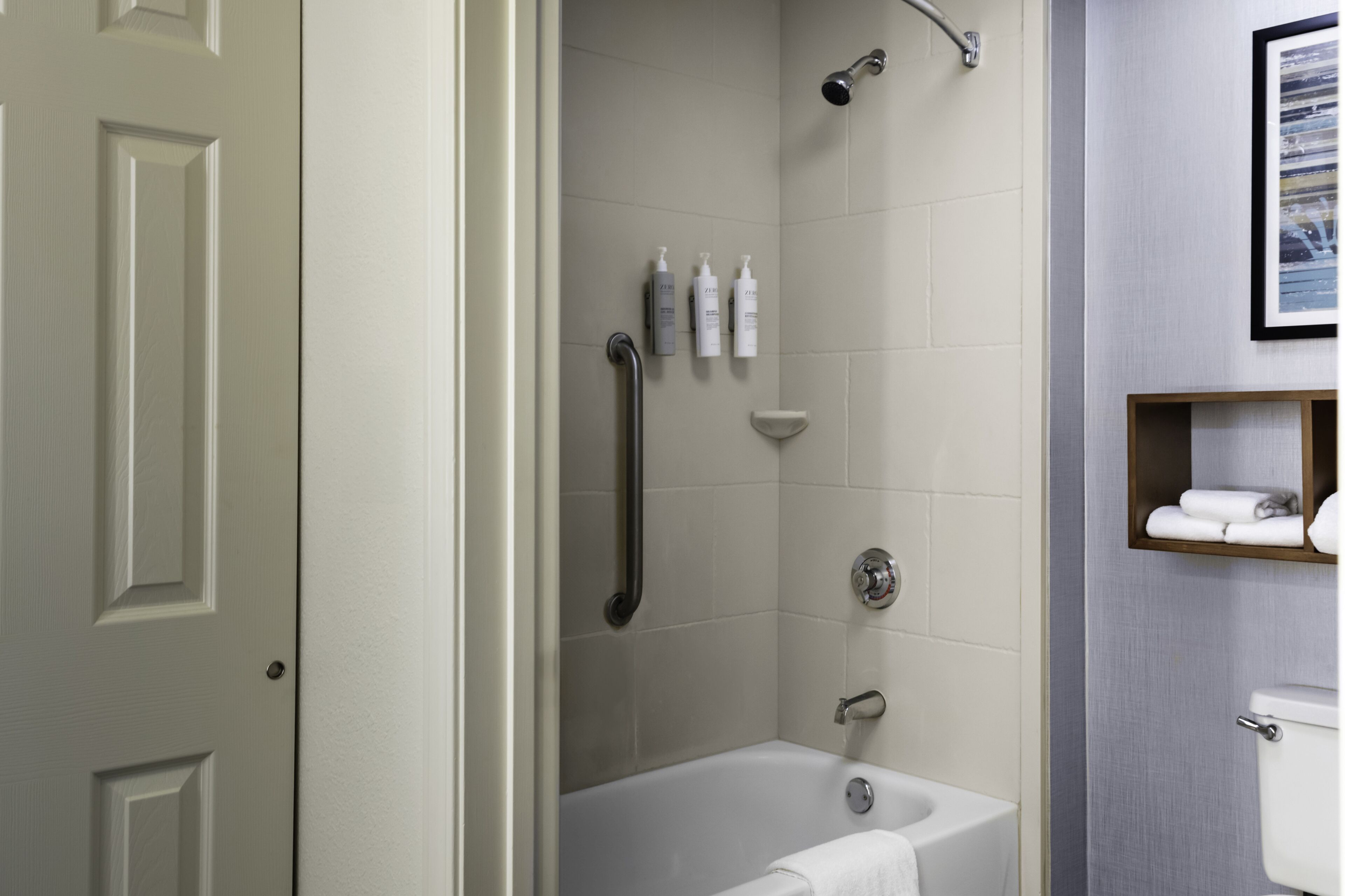 Ein Badezimmer mit einer Badewanne, einer Dusche und einem WC. An der Wand befinden sich Pflegeprodukte und ein Handtuchhalter.