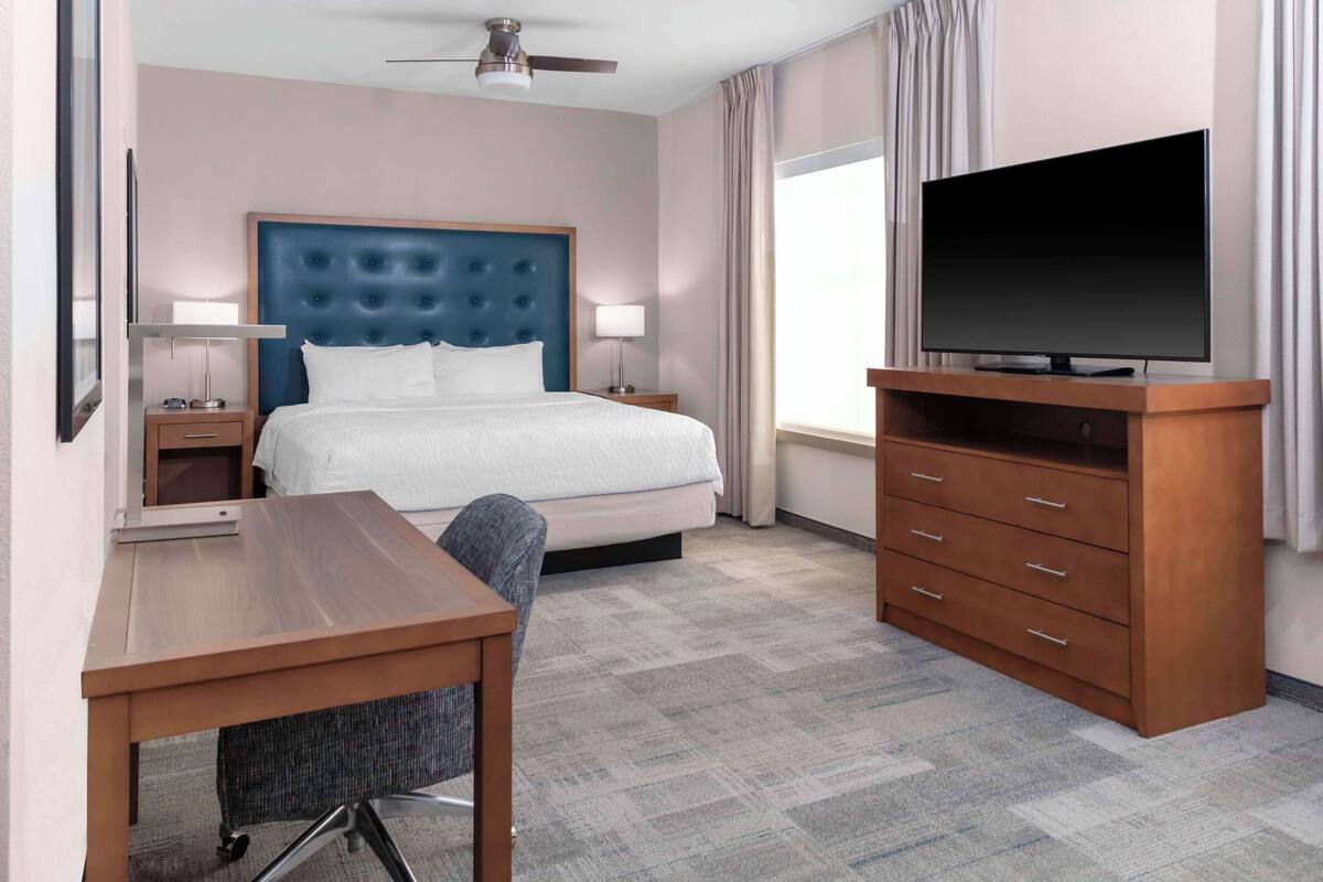 A hotel room with a bed, a desk, a television, and a wardrobe.