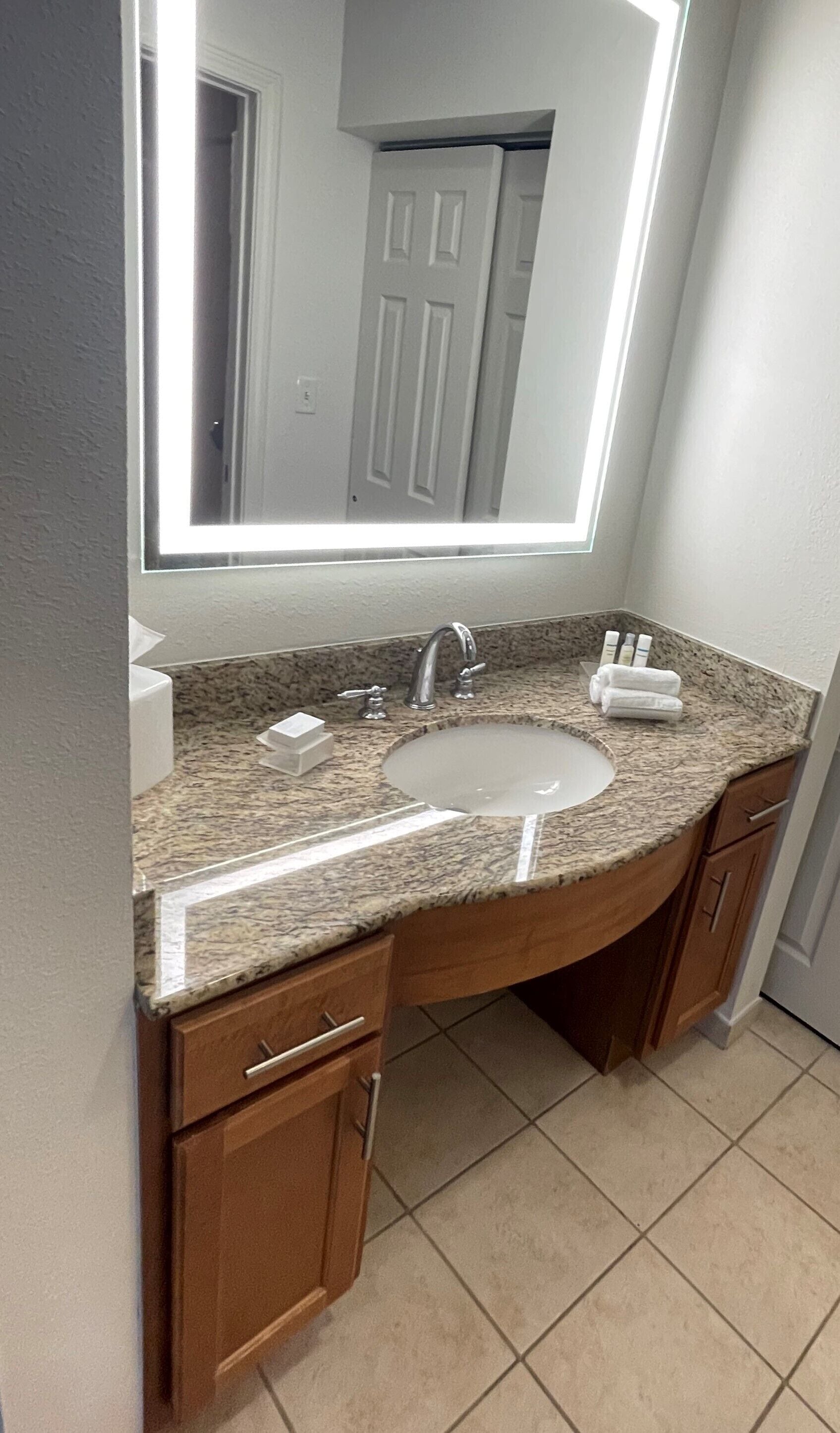 Une salle de bain avec un lavabo en granit, un miroir et des meubles en bois.