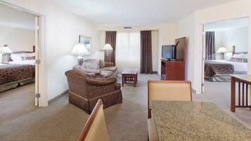 Une chambre d’hôtel comprenant un lit, un canapé, une table à manger, un téléviseur et un bureau.