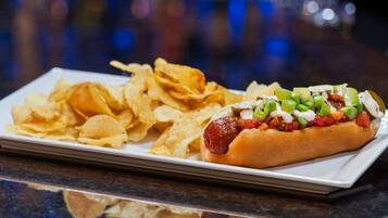 Ein Hotdog mit Belag und Pommes auf einem weißen Teller.
