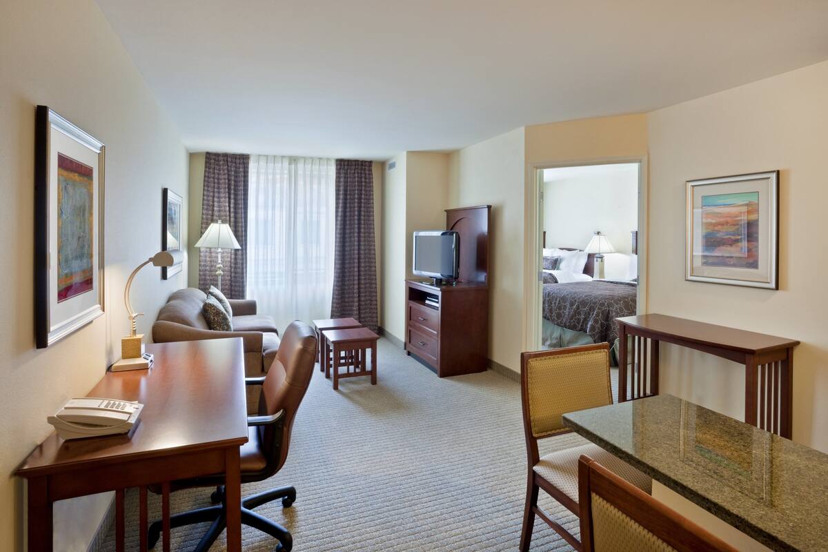 A hotel room with a desk, office chair, dining table, and a bed.