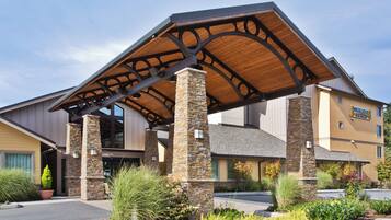 A hotel with a covered entrance, stone pillars, and a sign for 'Staybridge Suites.'